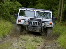 Серый Hummer H1 на грязной лесной дороге
